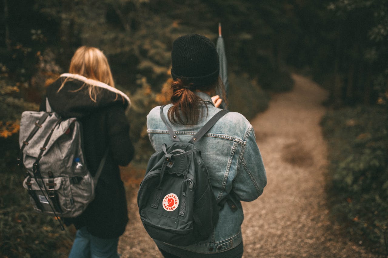 journey Two friends explore a forest trail together with backpacks, enjoying nature.